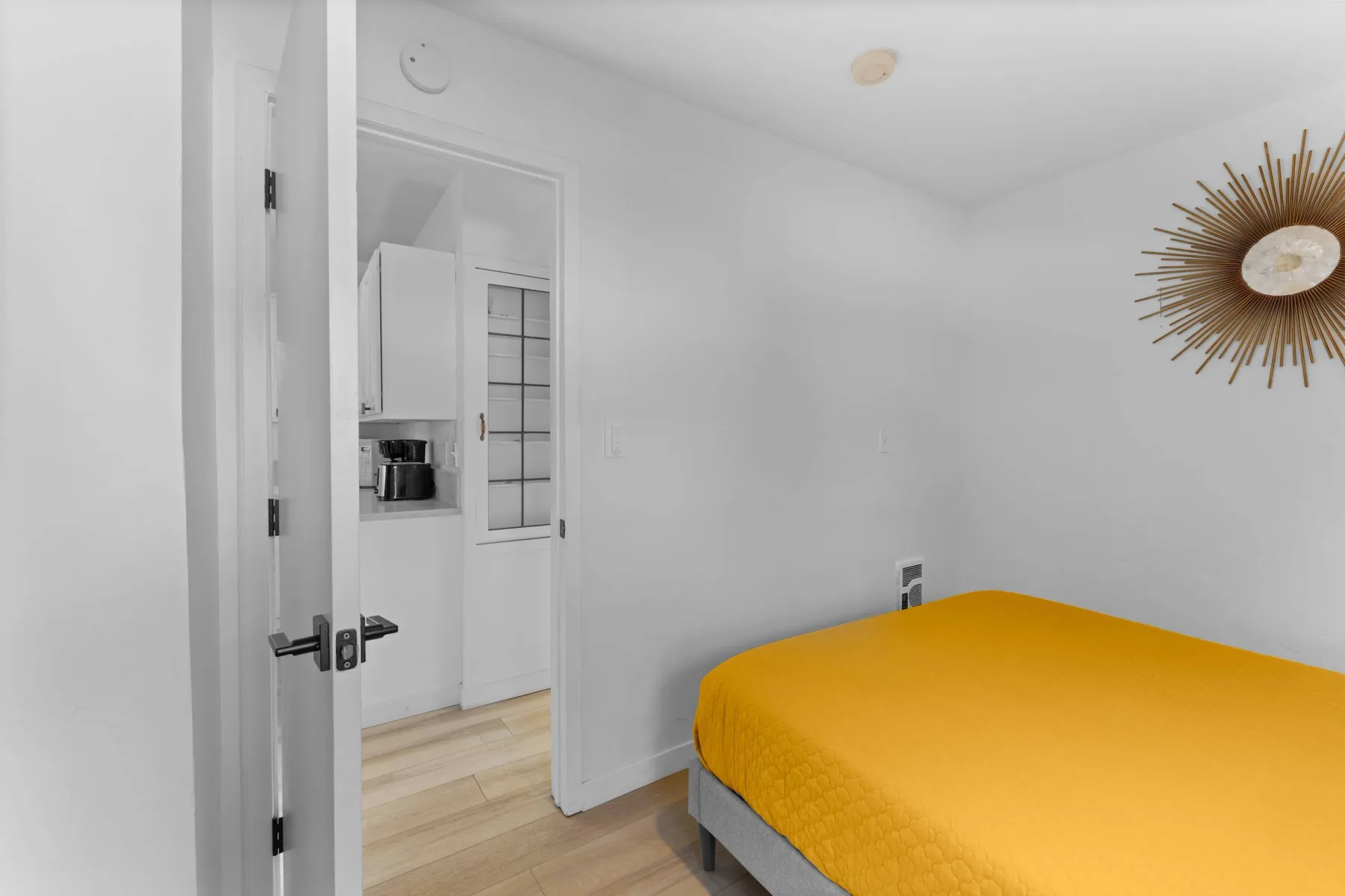 A bedroom with a bed covered in a bright yellow bedspread.