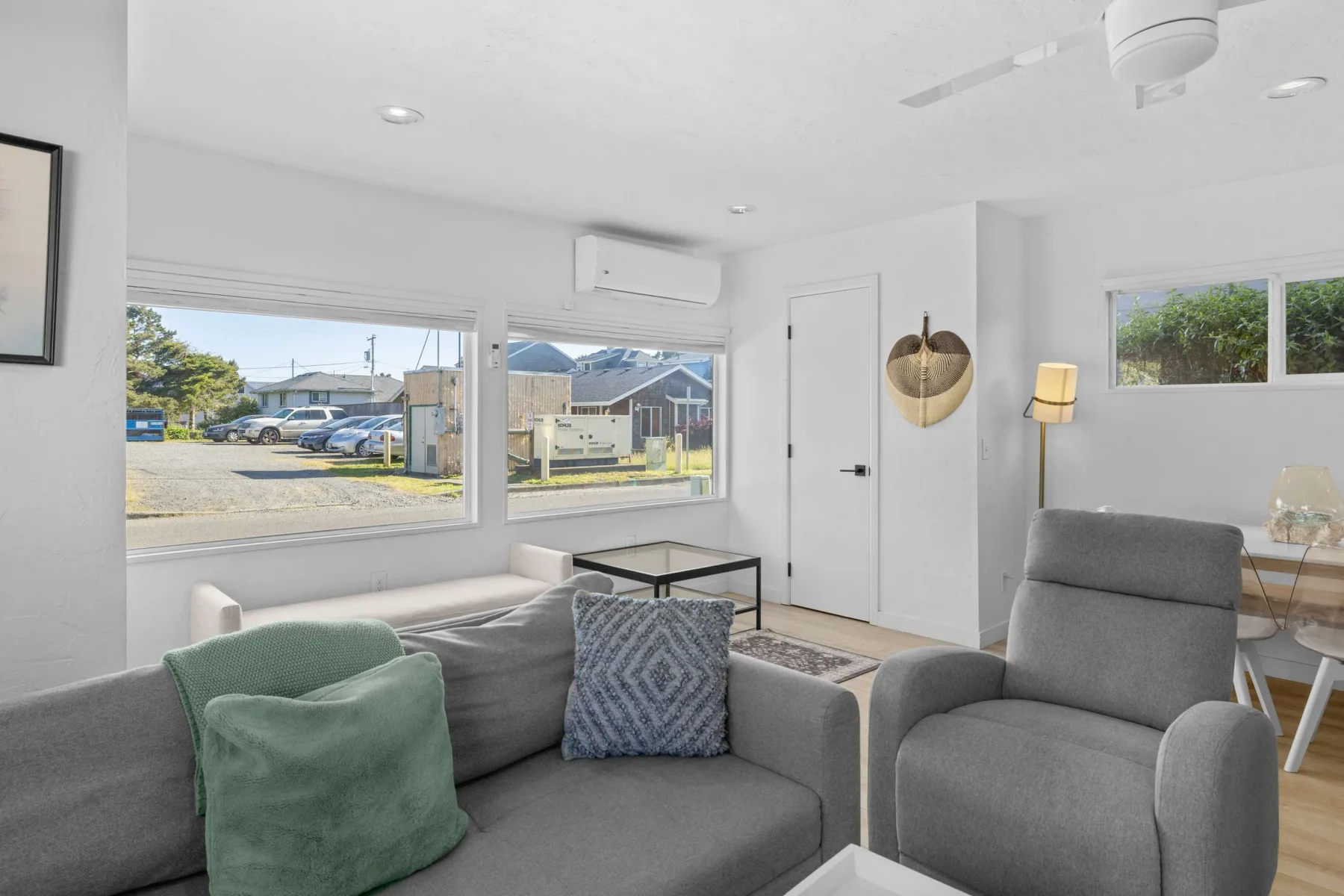 A bright living room with gray seating and large windows.