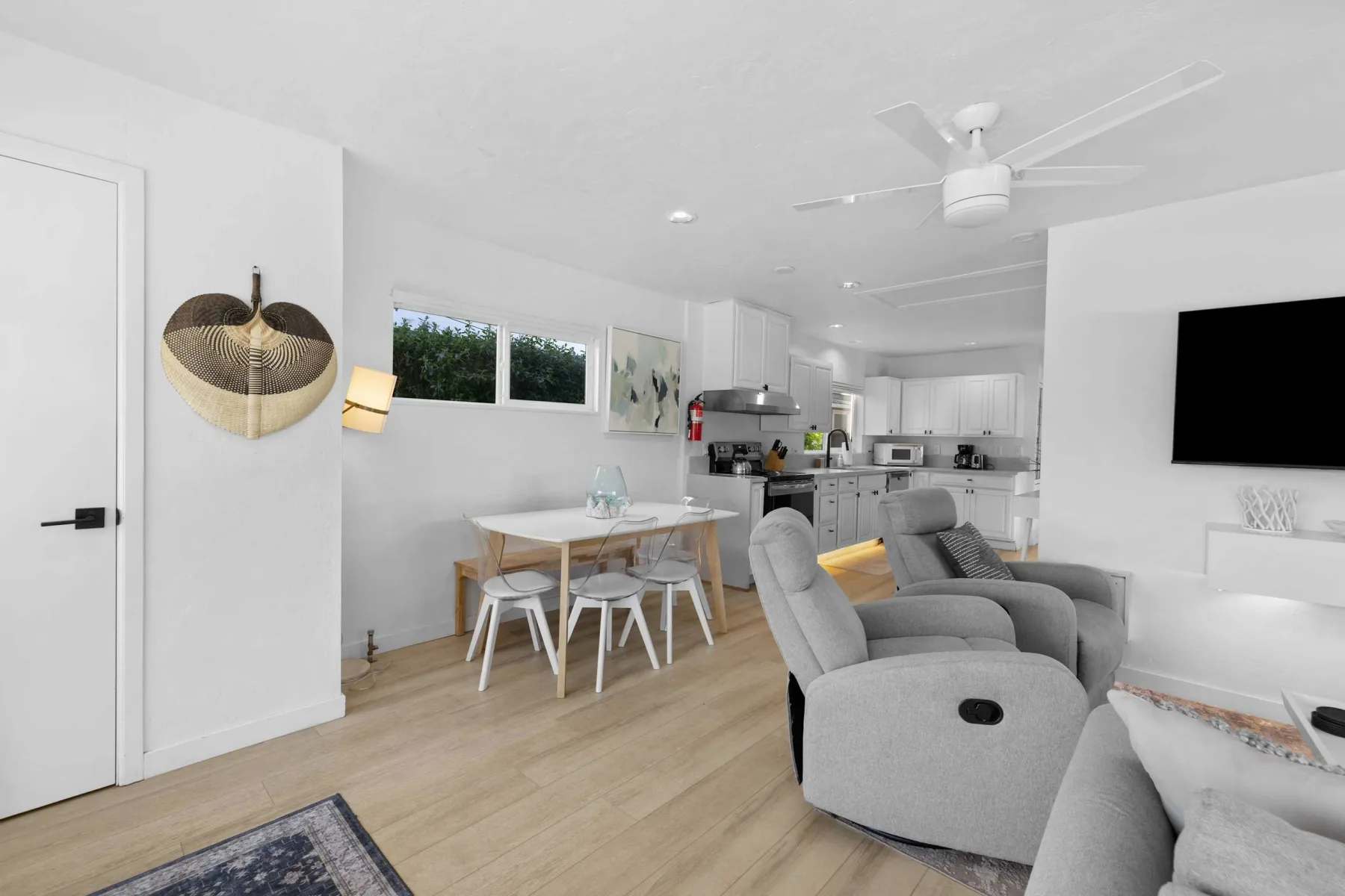 A bright open-plan living and dining area with a kitchen in the background.