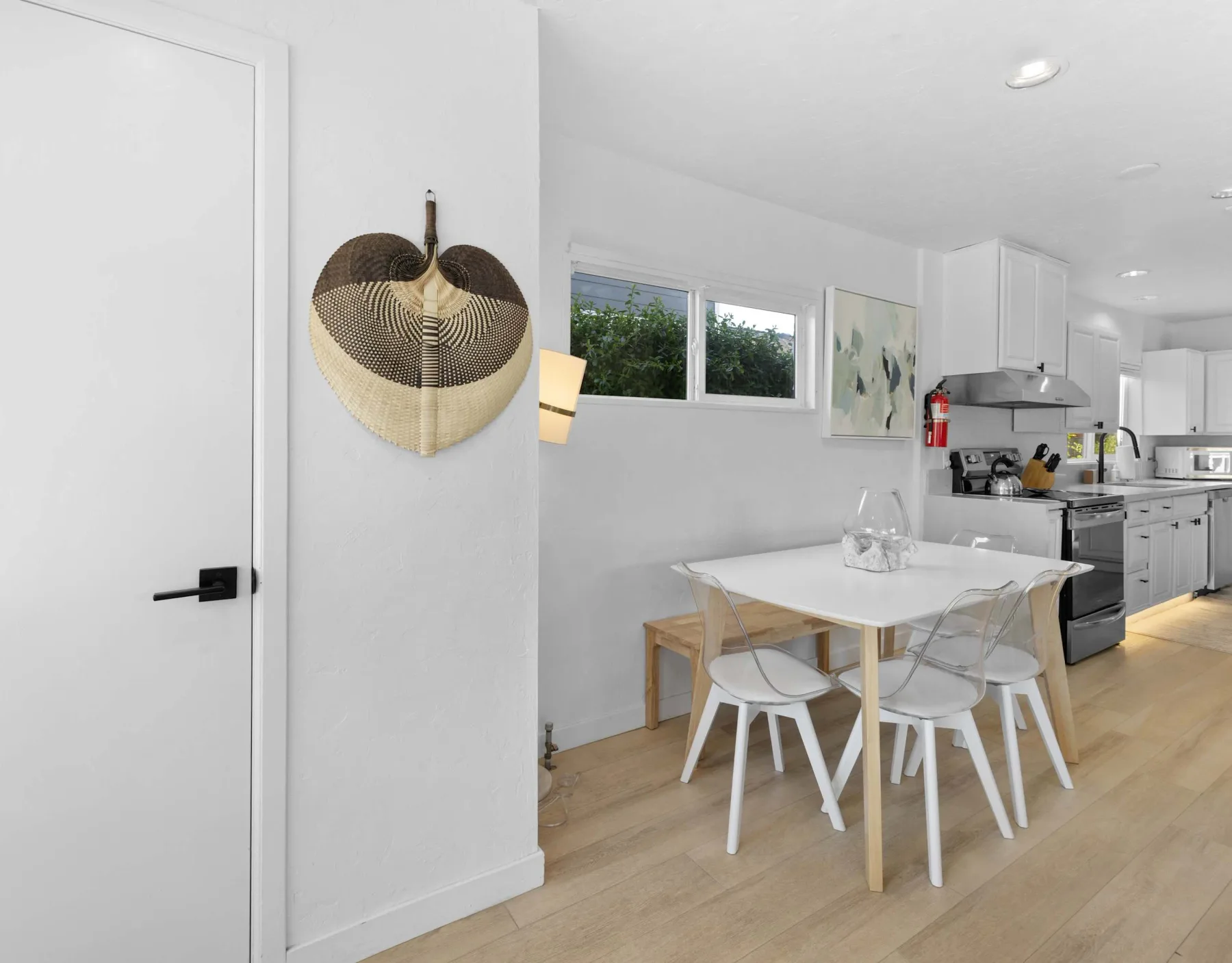 A bright kitchen and dining area with a white table and contemporary cabinetry.