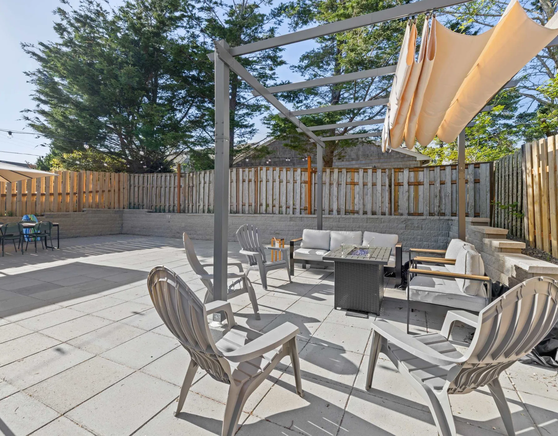 An outdoor patio with seating, a table, and a fabric shade structure.