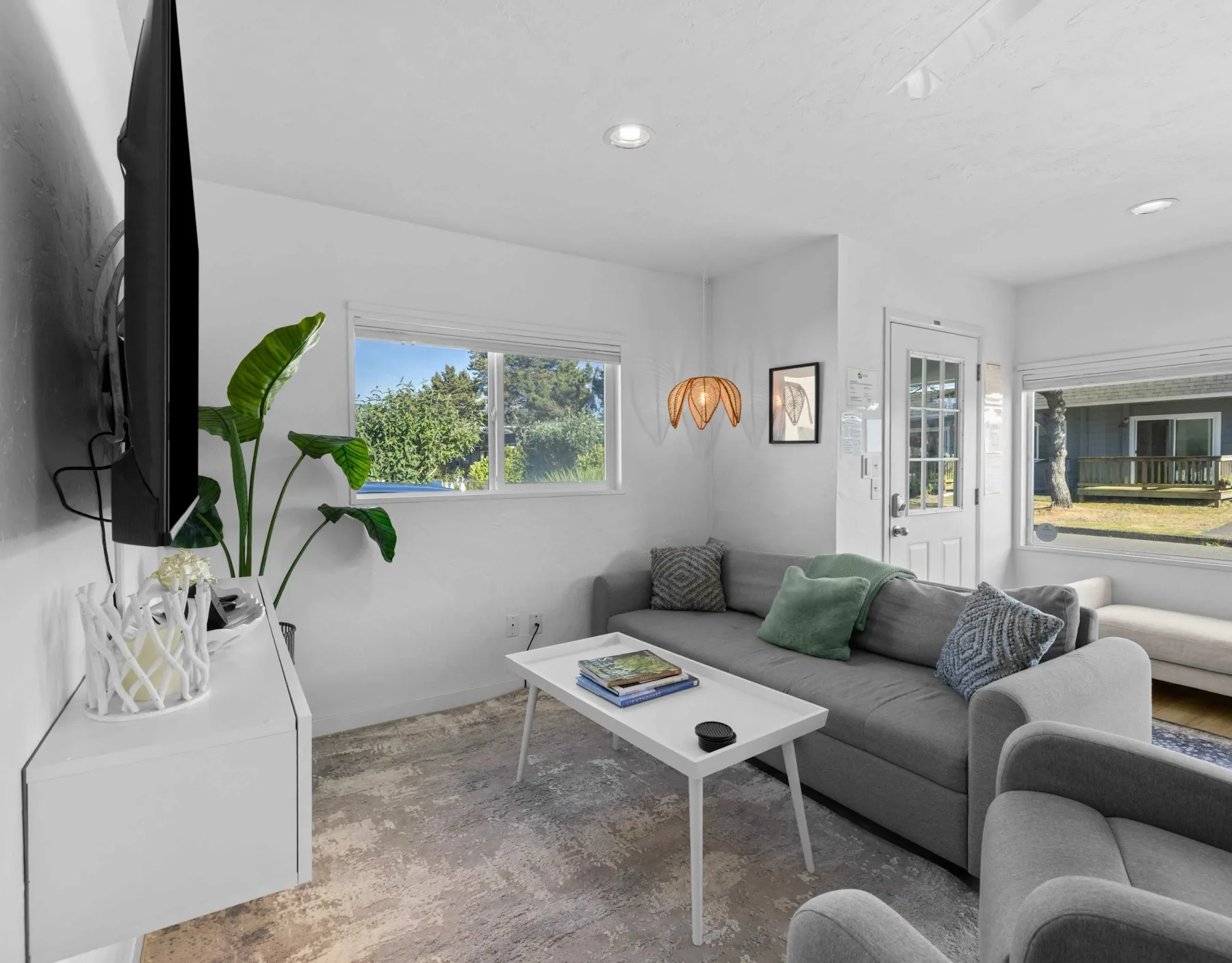 A bright living room with gray seating, a coffee table, and a large window.