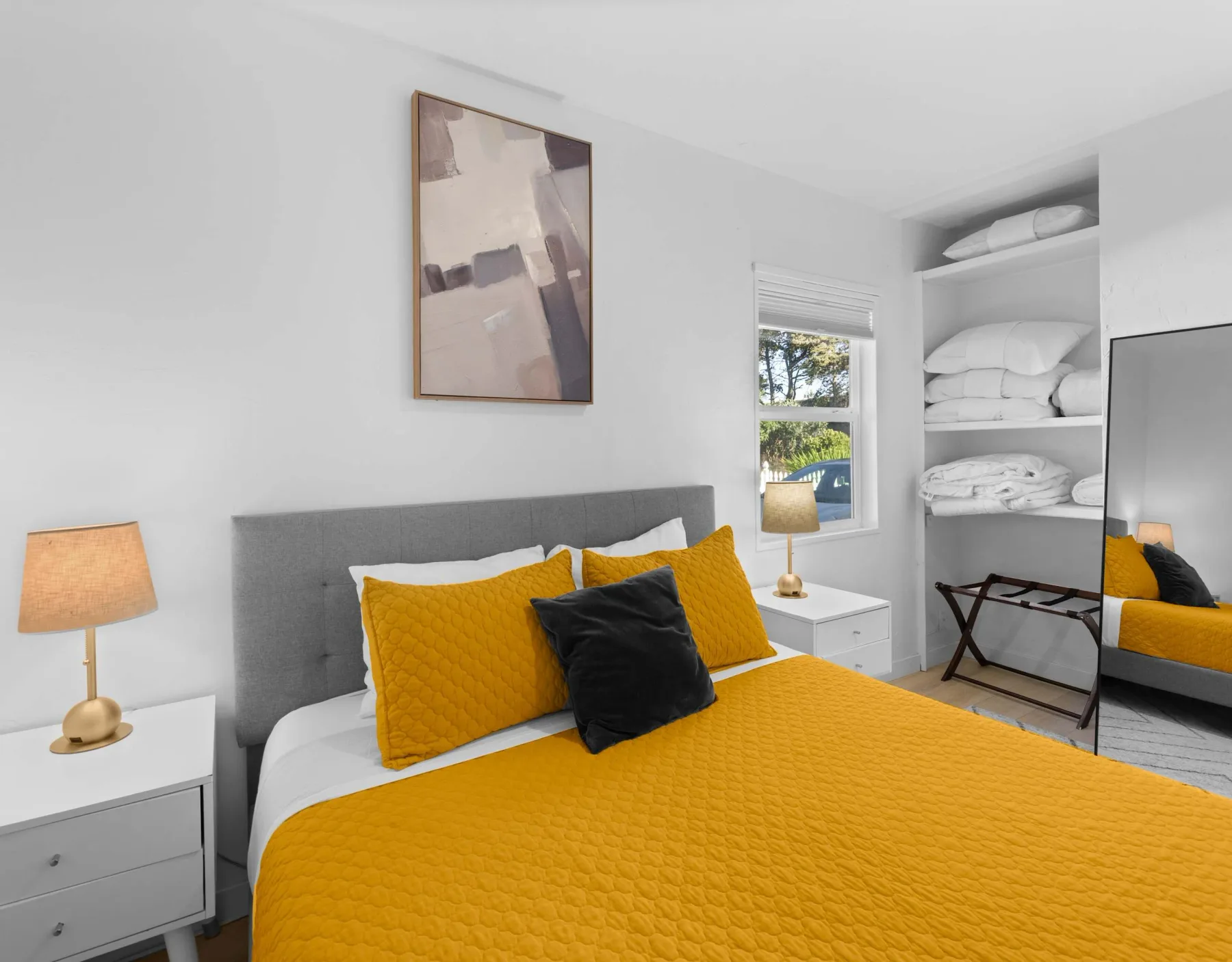 A bedroom with a bed dressed in a bright yellow quilt and pillows.