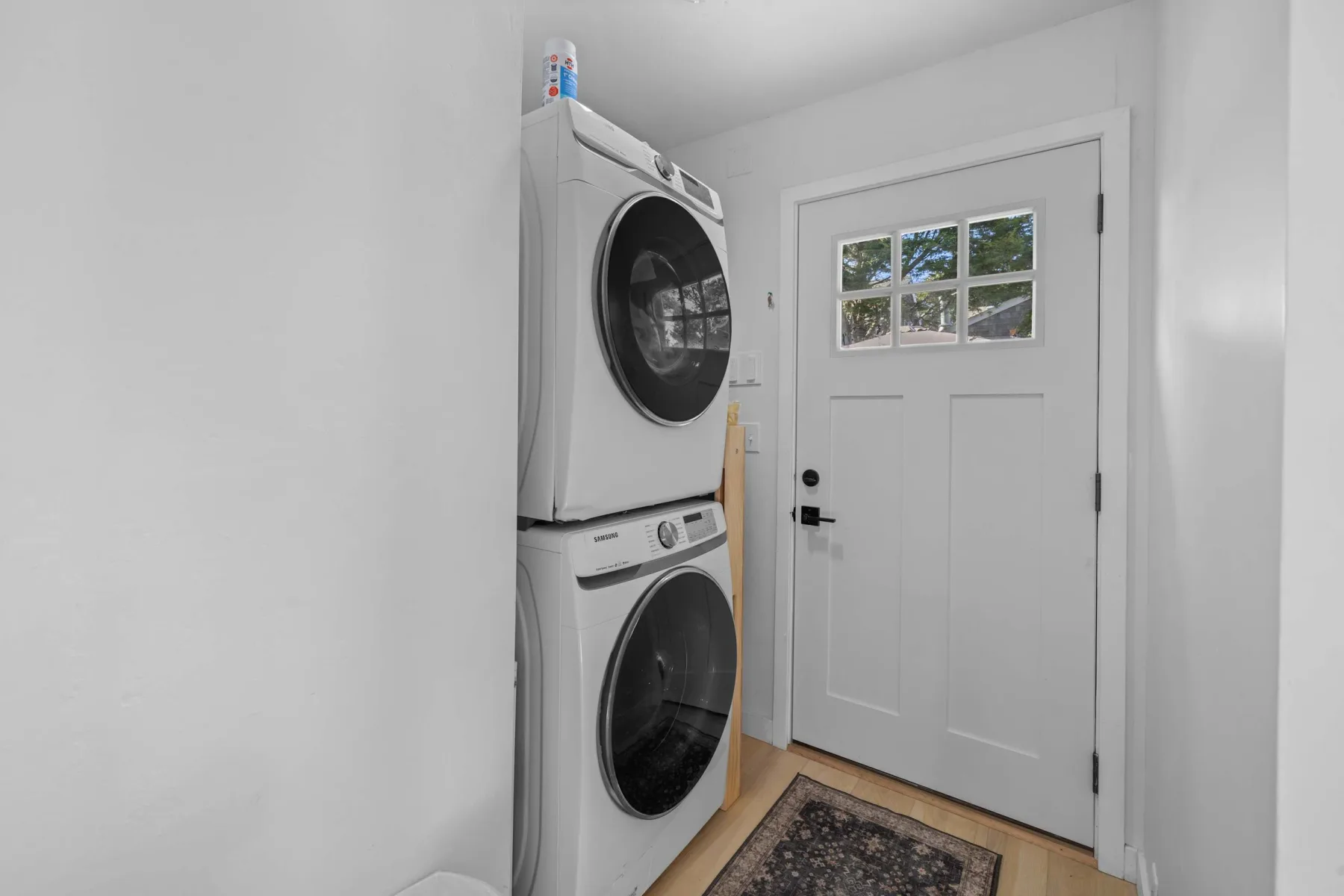 A laundry area with a stacked washer and dryer beside a white door.