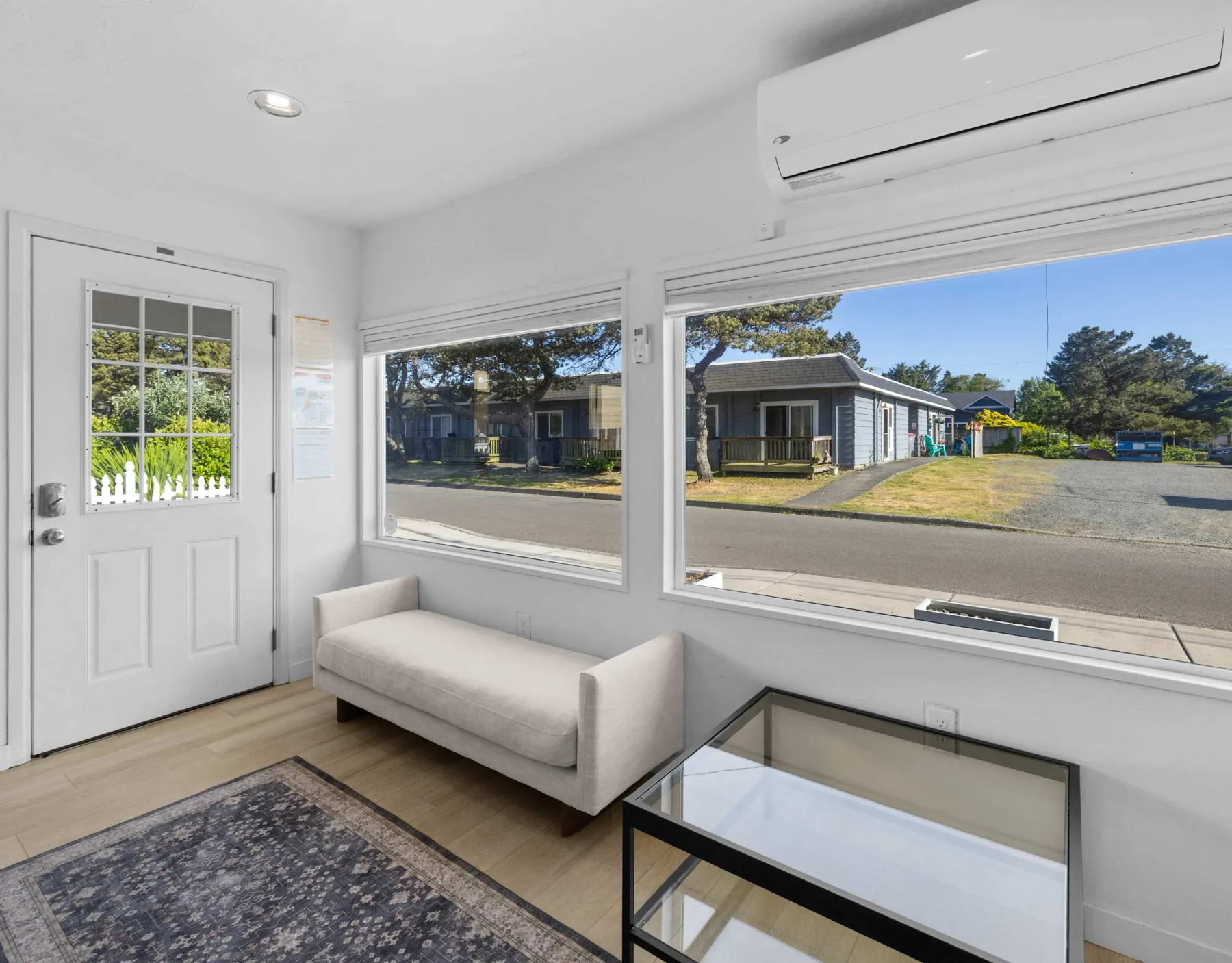 A bright sitting area with large windows overlooking a street.