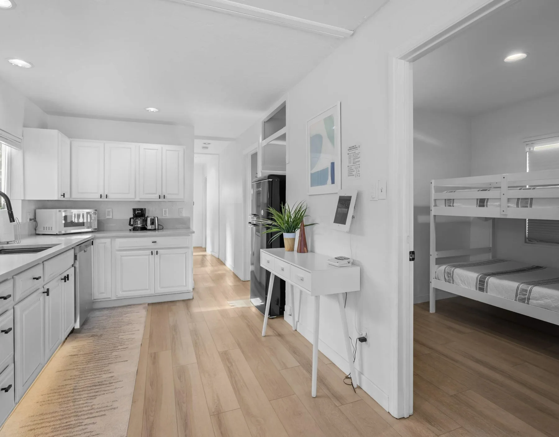 A bright kitchen opens onto a bedroom with bunk beds and a small desk.