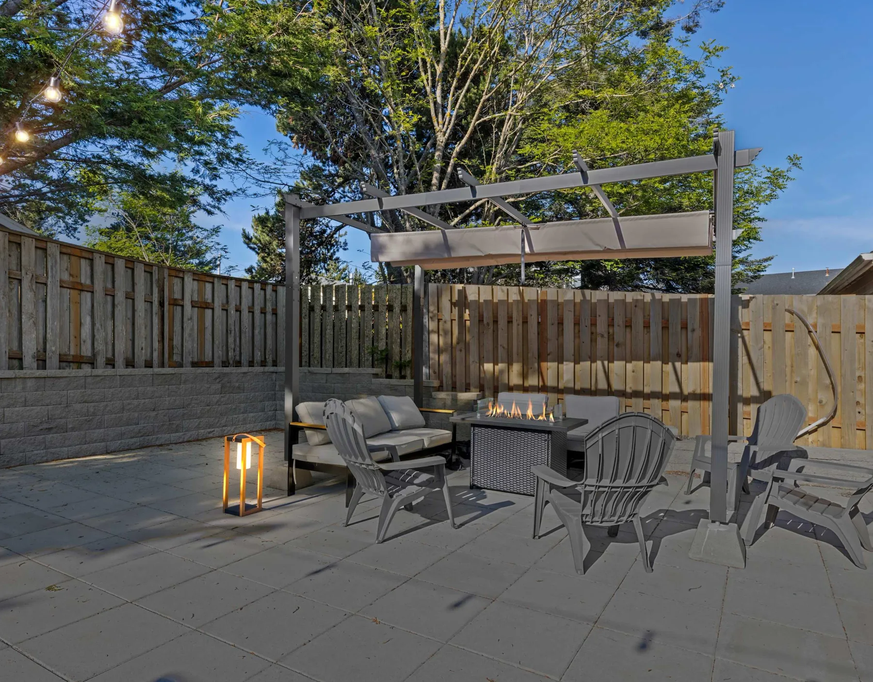 Outdoor patio seating surrounds a fire table beneath a pergola.