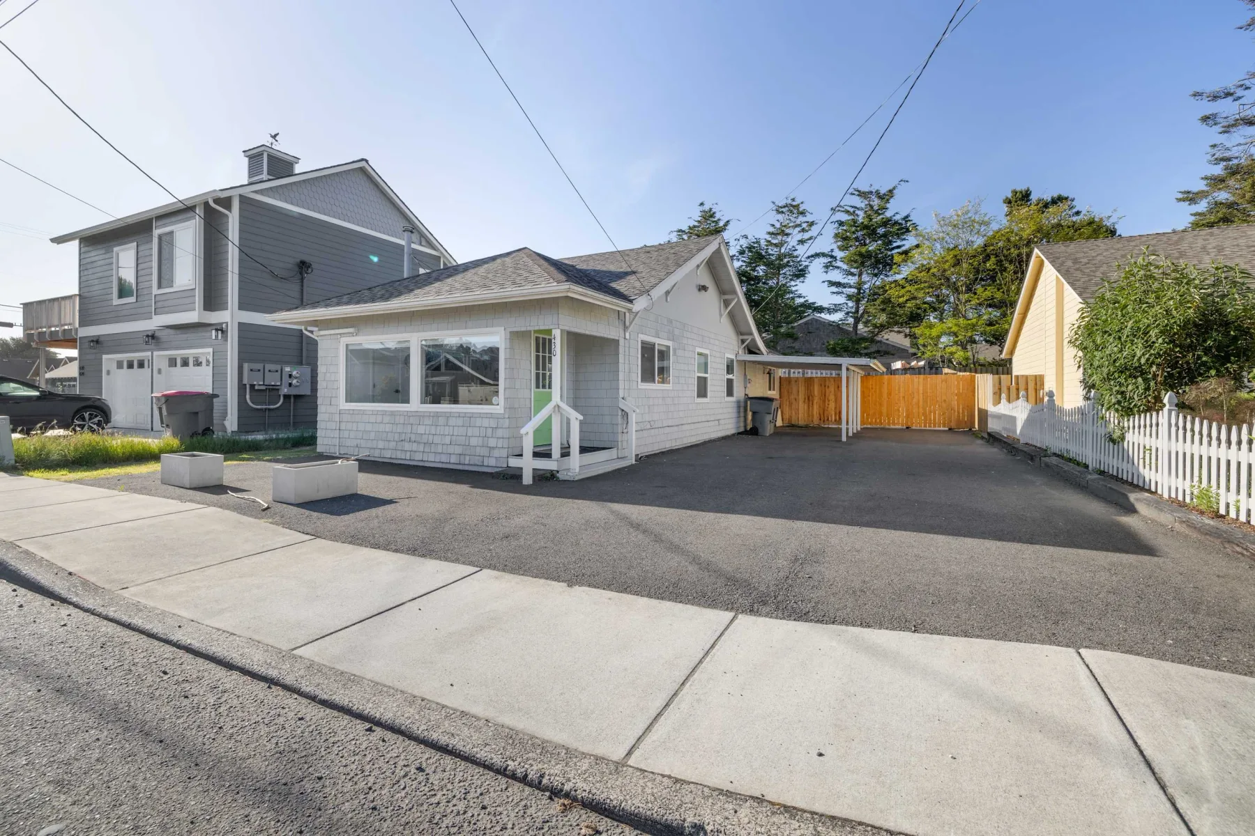 A residential driveway and paved parking area sit between neighboring houses.