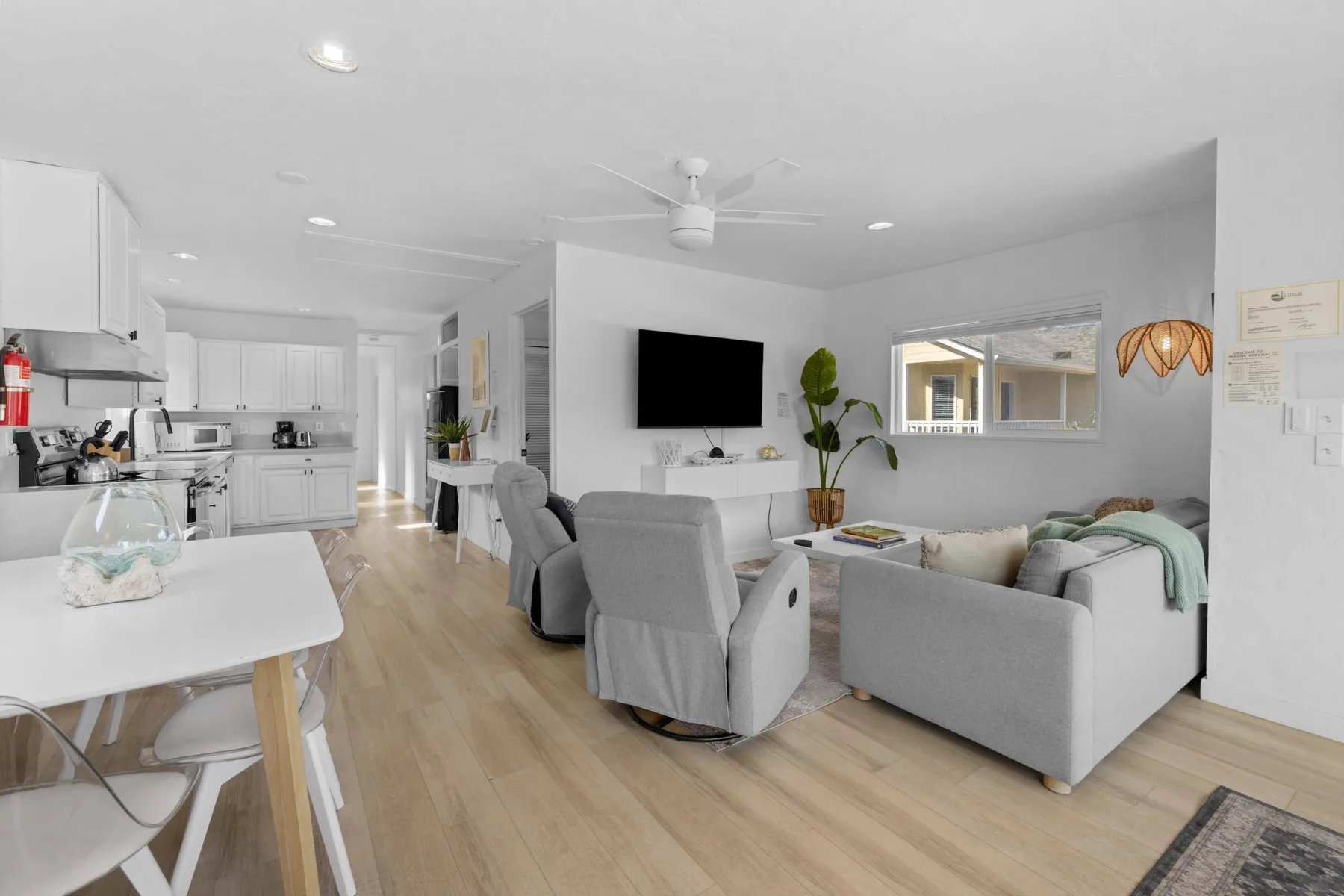 An open-plan living room and kitchen with light-colored seating and a dining table.