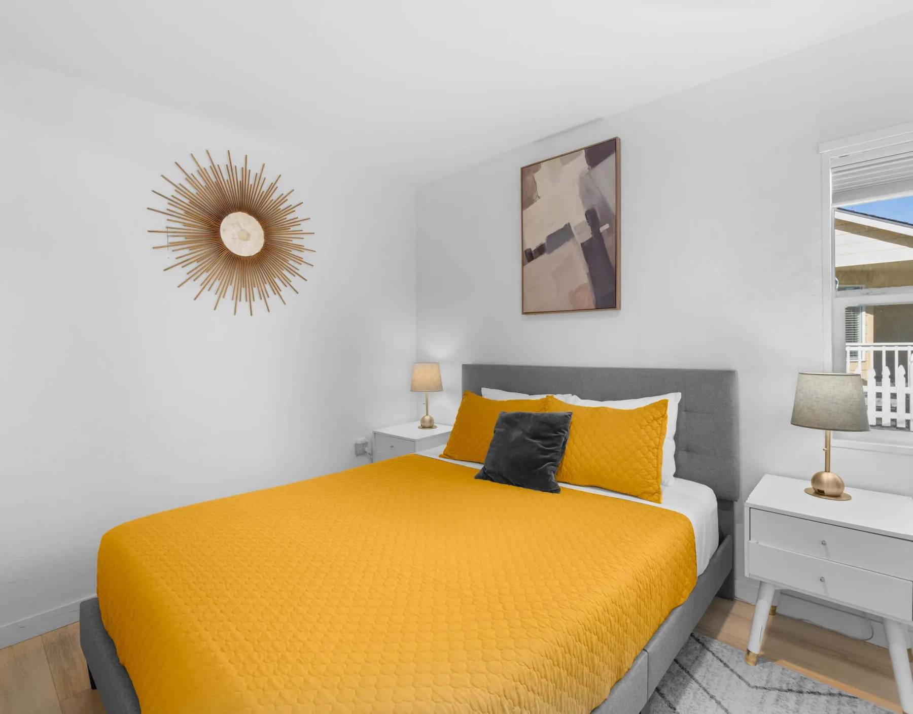 A bright bedroom with a bed covered in a mustard-yellow quilt.
