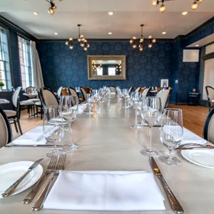 Espacio representativo del hotel: Un comedor está dispuesto con mesas largas preparadas para una comida.