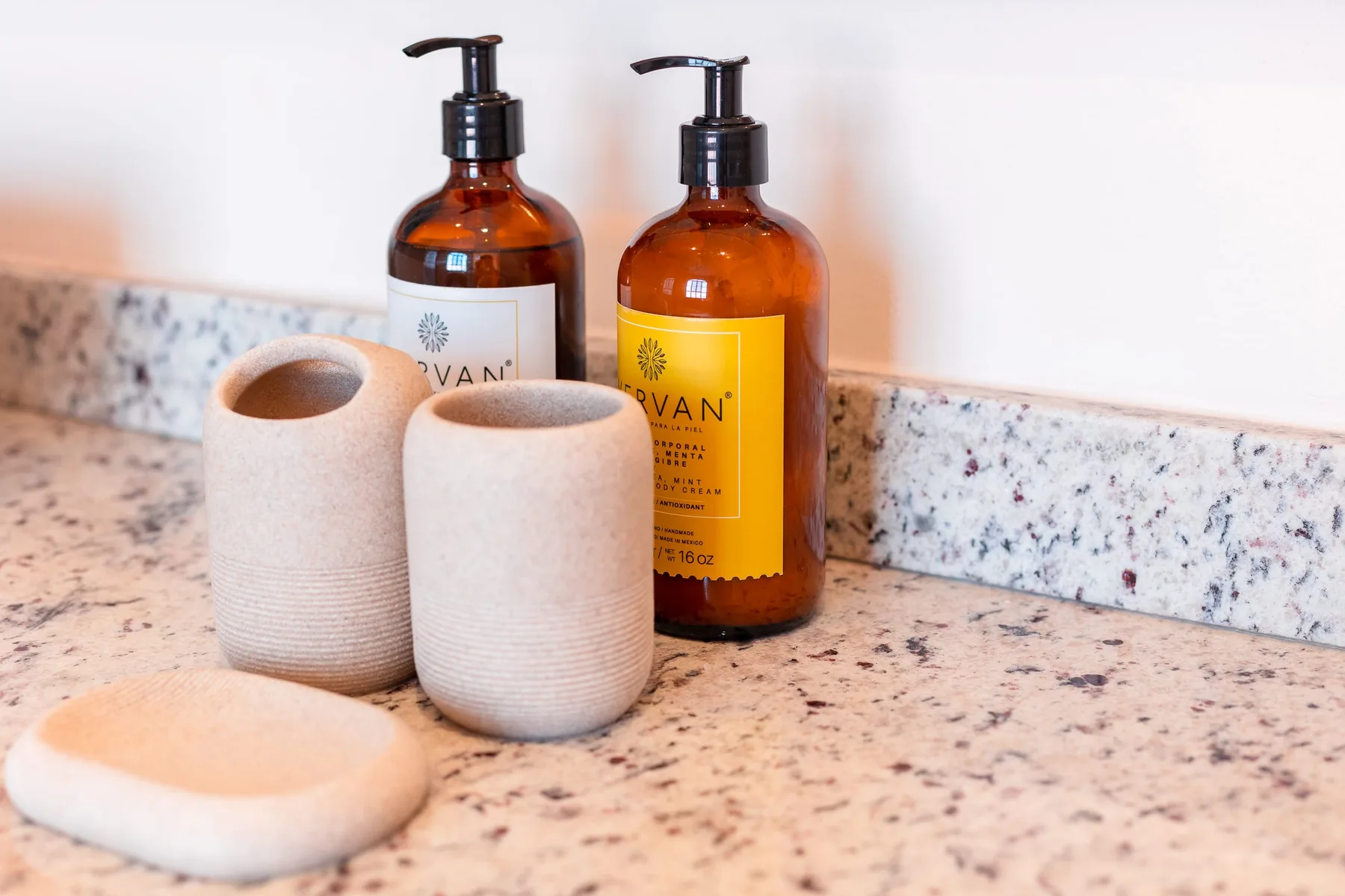 Encimera de baño con botellas ámbar con dosificador y accesorios de cerámica.