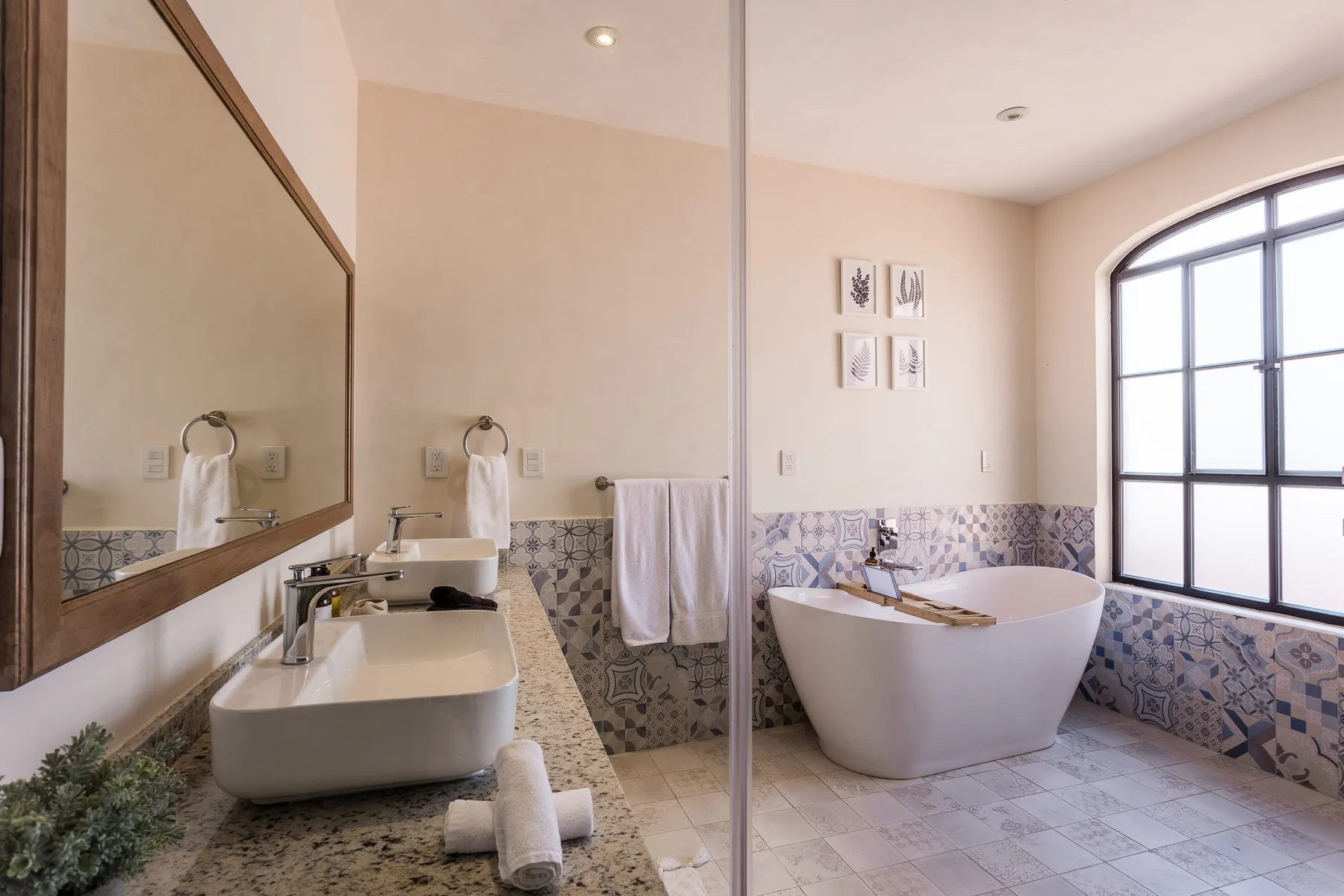 Un baño luminoso con bañera exenta, lavabo y una gran ventana arqueada.