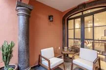 Una zona de estar interior tiene dos sillones junto a una gran ventana arqueada.