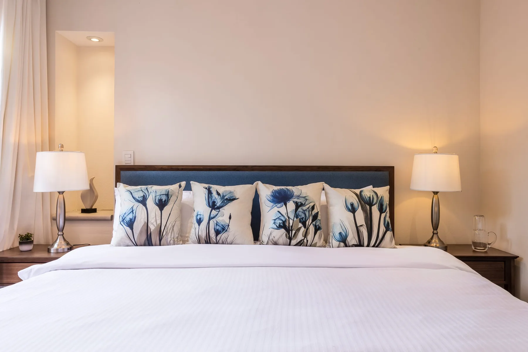 Un dormitorio con una cama bien hecha y almohadas con estampado floral.