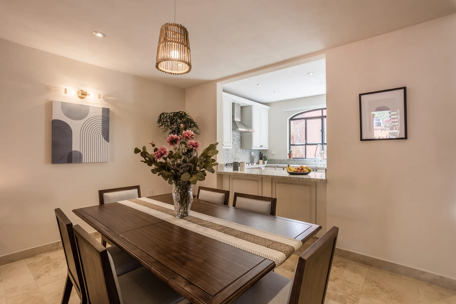 Comedor con una mesa de madera oscura y vista abierta hacia la cocina.