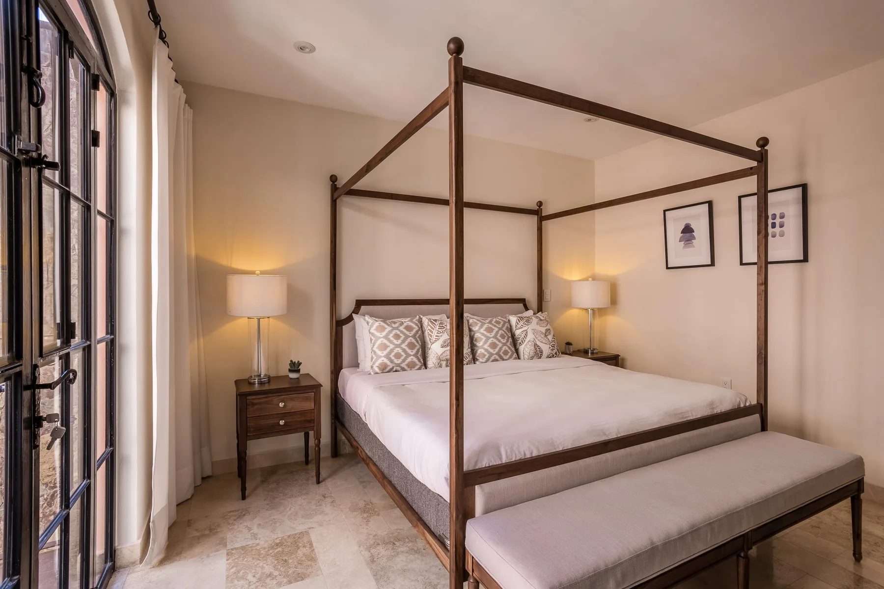 Un dormitorio con una cama con dosel y un banco a los pies.