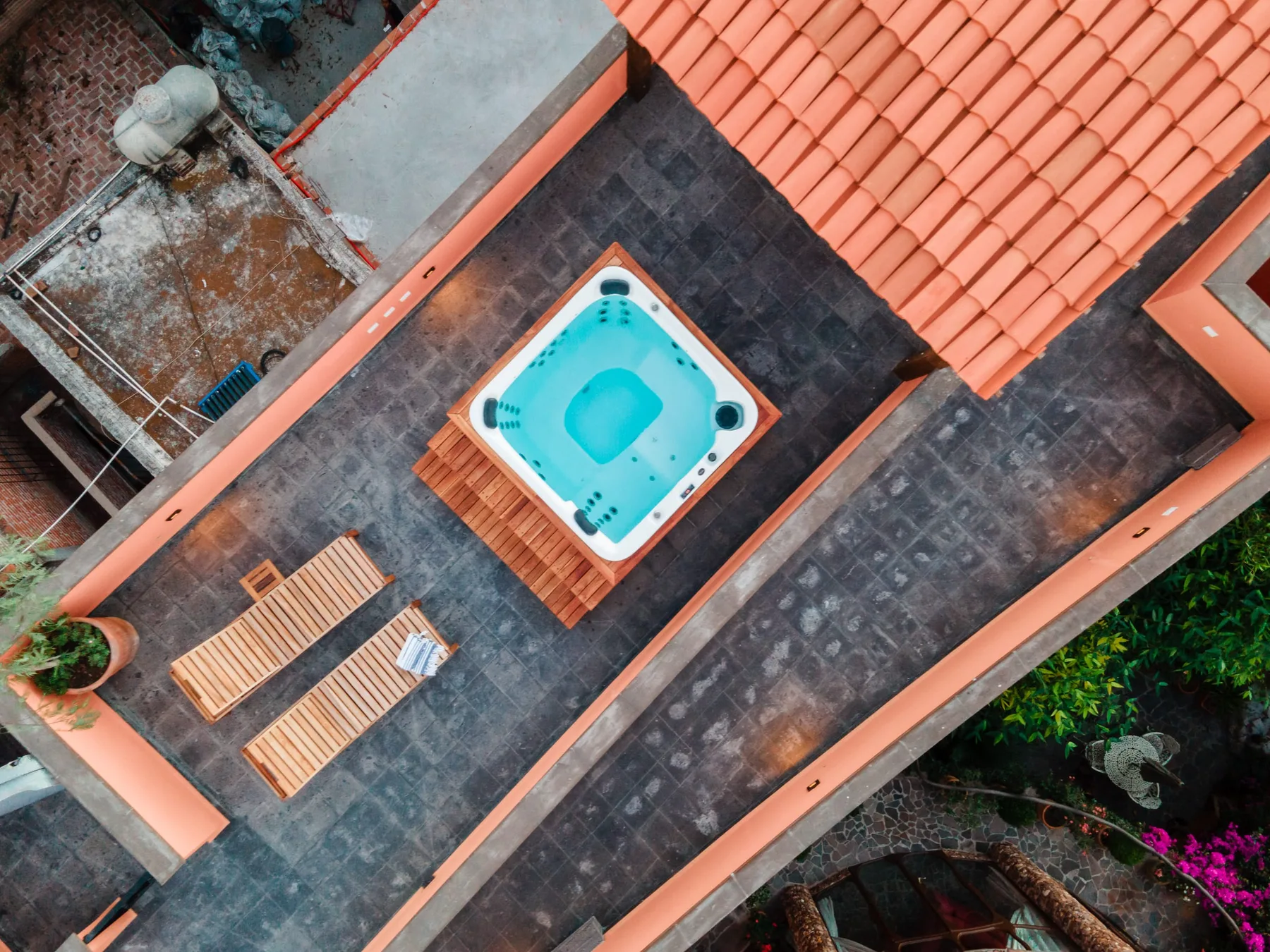 Zona común: Una terraza exterior en la azotea con una bañera de hidromasaje y tumbonas de madera.