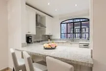 Una cocina luminosa con una amplia isla y grandes ventanas.