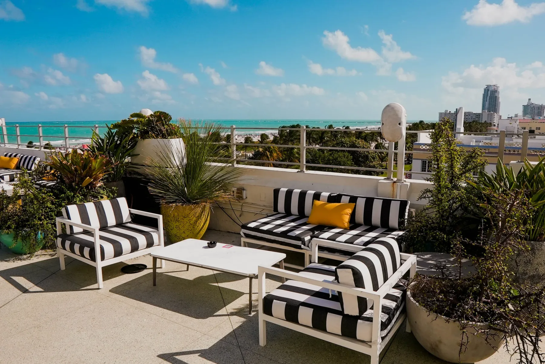 Representative hotel space: A rooftop terrace has striped outdoor seating, potted plants, and a view of the sea.
