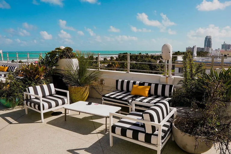 Representative hotel space: A rooftop terrace has striped seating, potted plants, and a view of the sea.