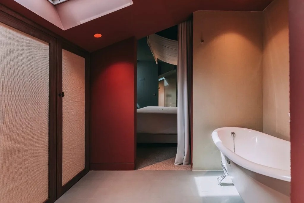 Espacio representativo del hotel: Un baño con una bañera exenta junto a una puerta abierta.