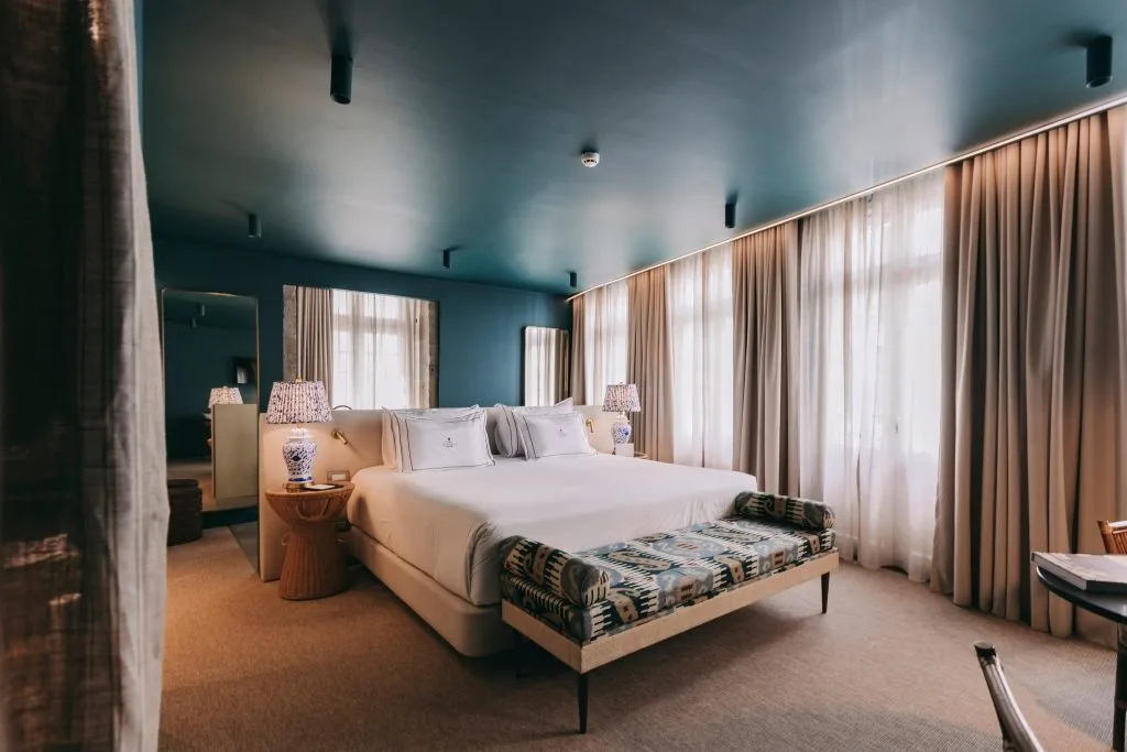 Espacio representativo del hotel: Un dormitorio con una cama grande, mesitas de noche y cortinas largas.