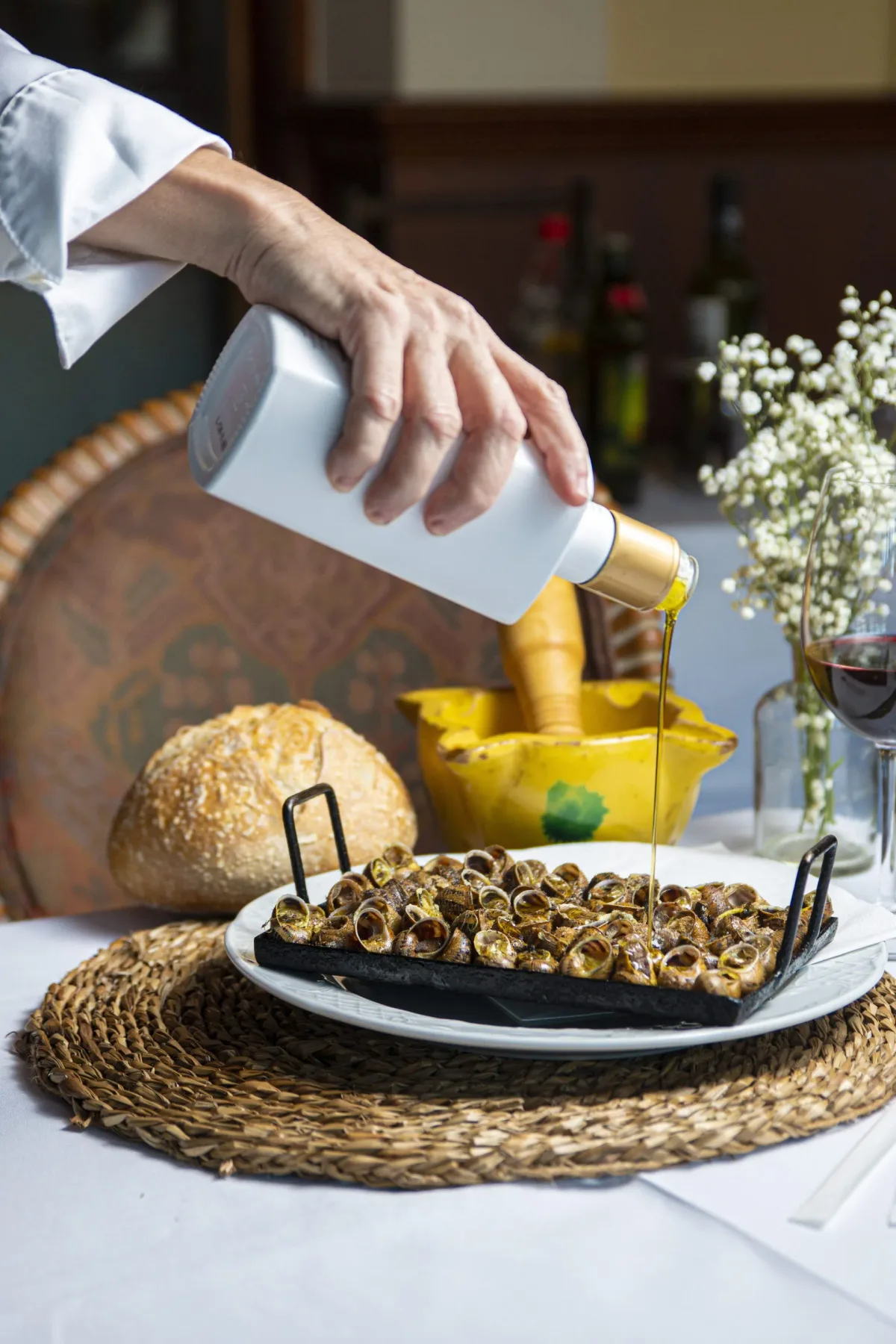 Espacio representativo del hotel: Una mesa muestra una fuente de caracoles mientras se vierte aceite sobre ellos.