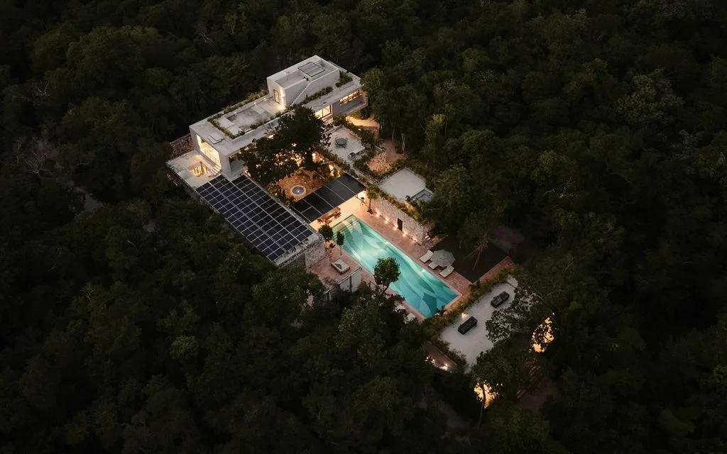 Vista aérea de una propiedad rodeada de bosque con una piscina color turquesa.