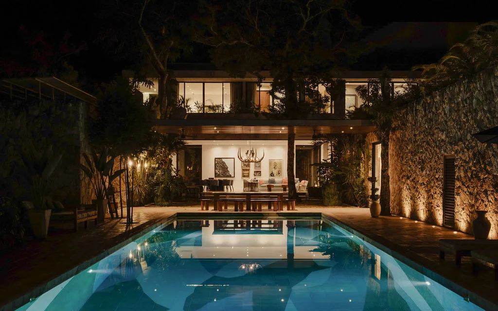 A swimming pool in front of a warmly lit building at night.