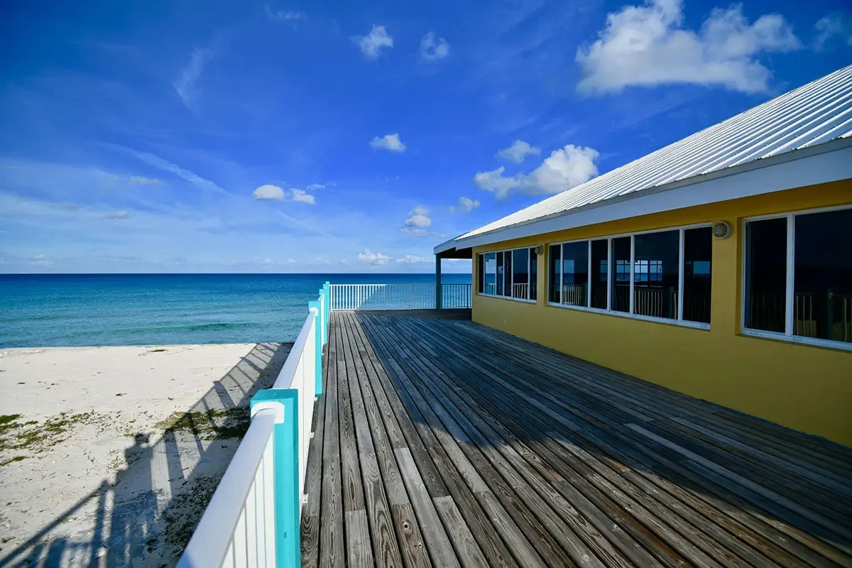 Espacio representativo del hotel: Un edificio junto a la playa da a una larga terraza de madera junto al mar.