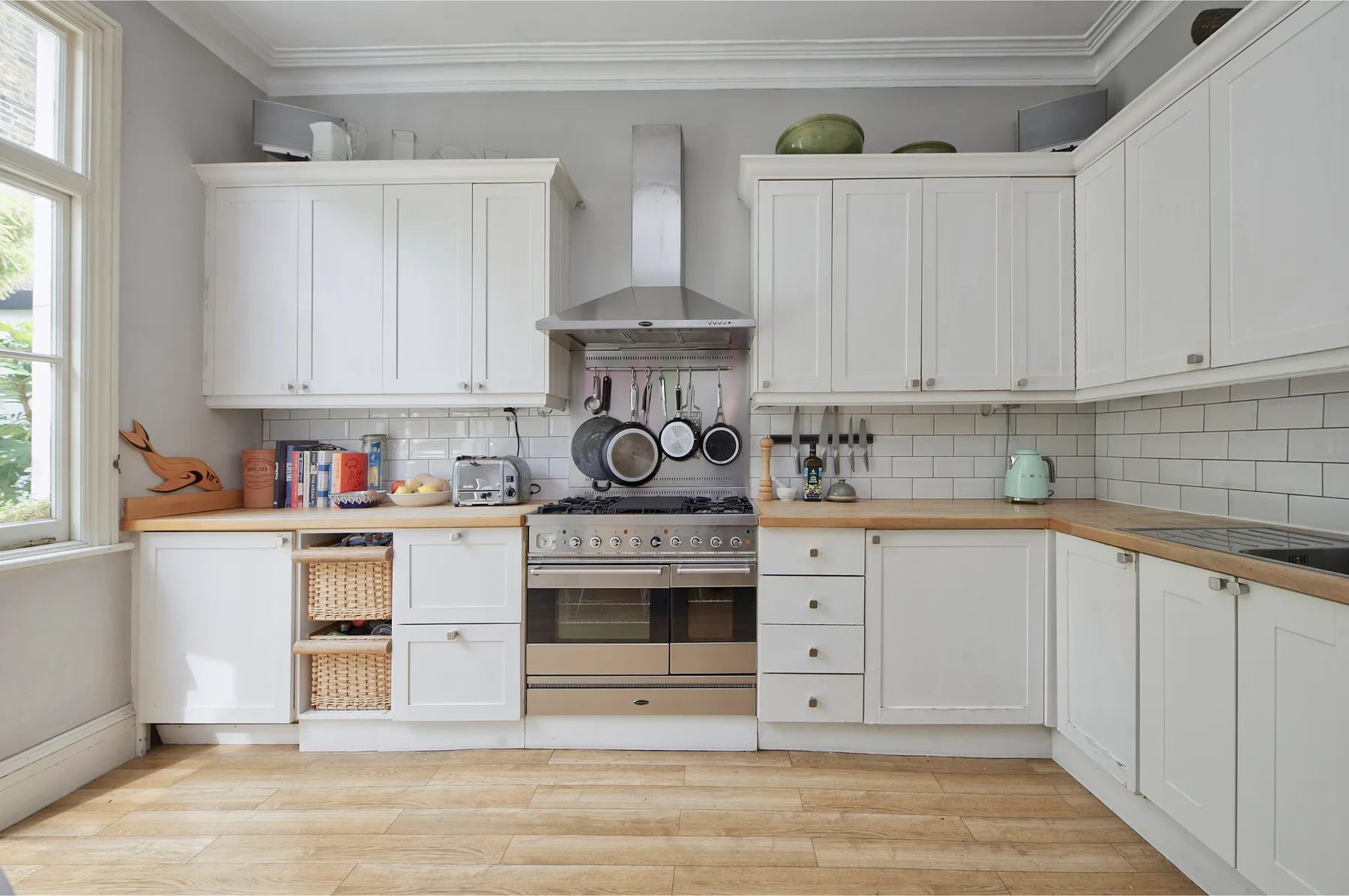 Una cocina luminosa con gabinetes blancos, una estufa y una encimera de madera.