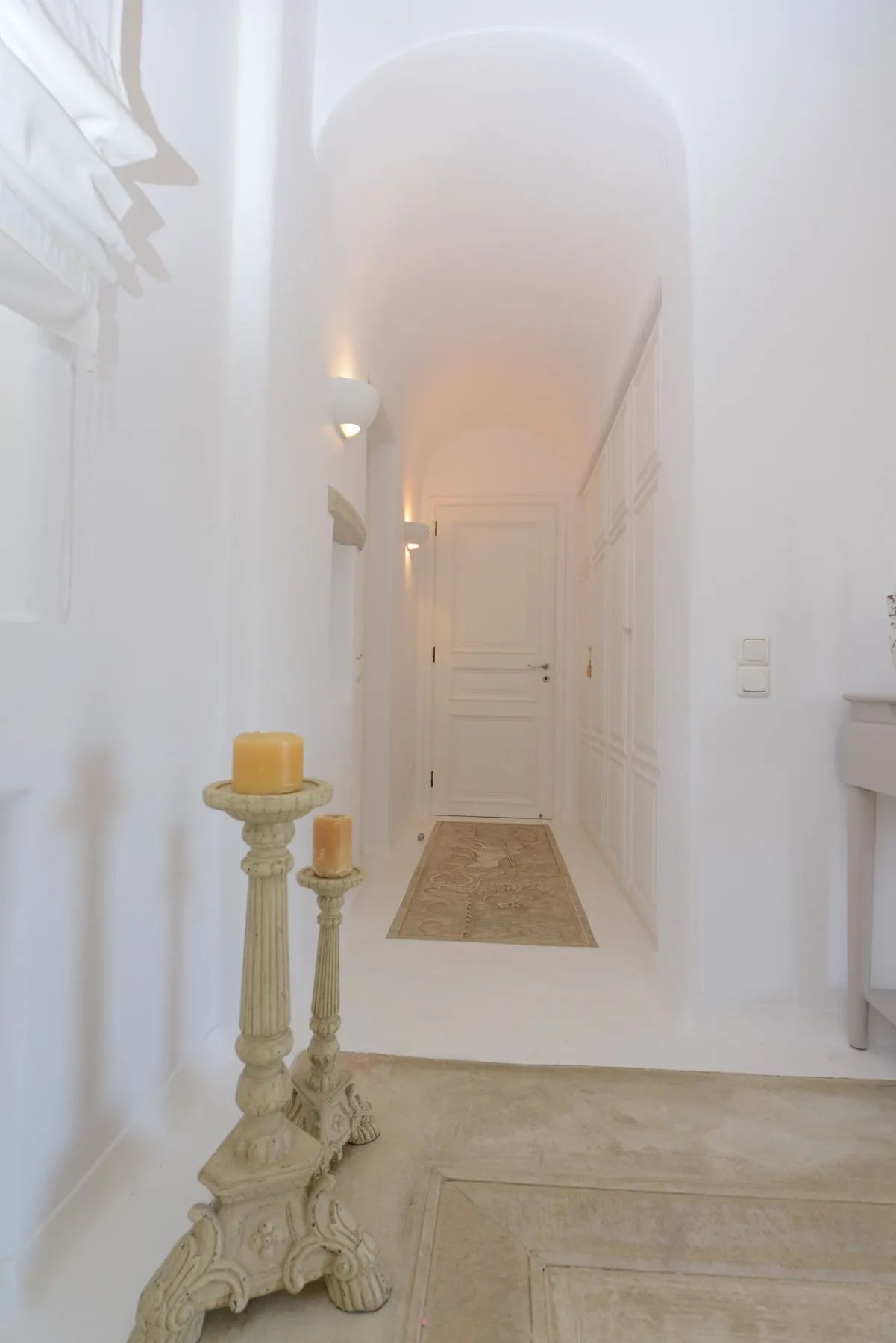 A bright hallway with a rug and a white door at the far end.