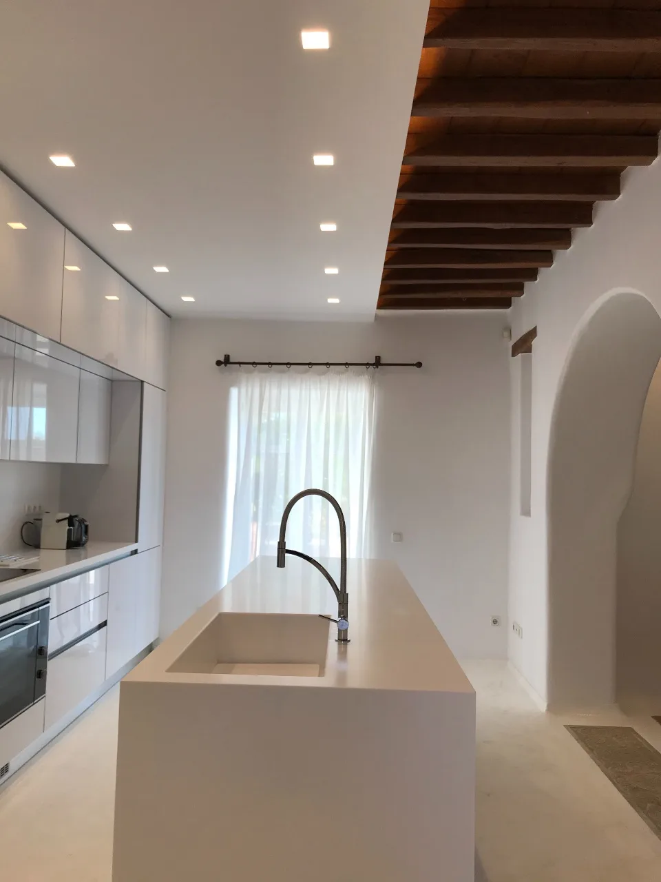 A bright modern kitchen with a central island and a large window.