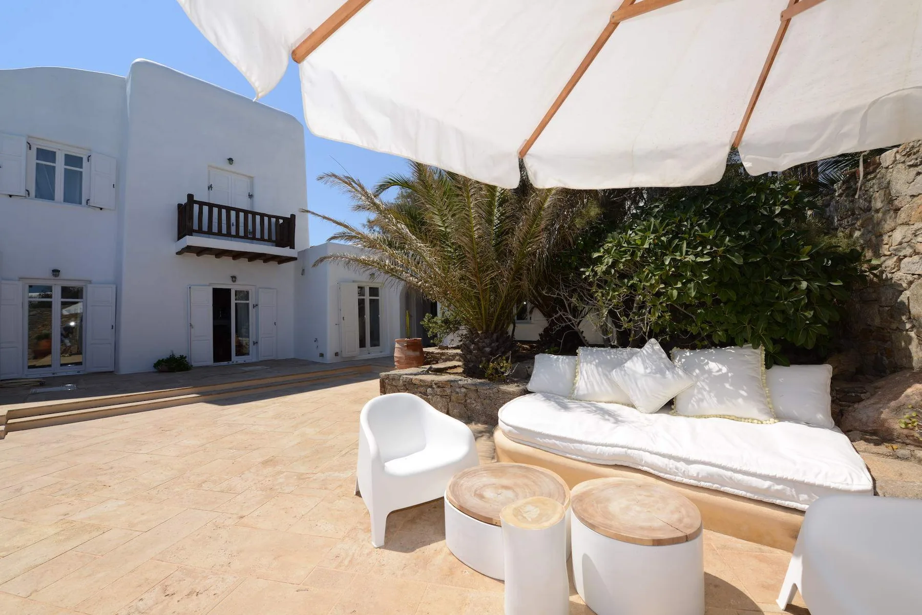 An outdoor patio has cushioned seating beneath a white canopy.