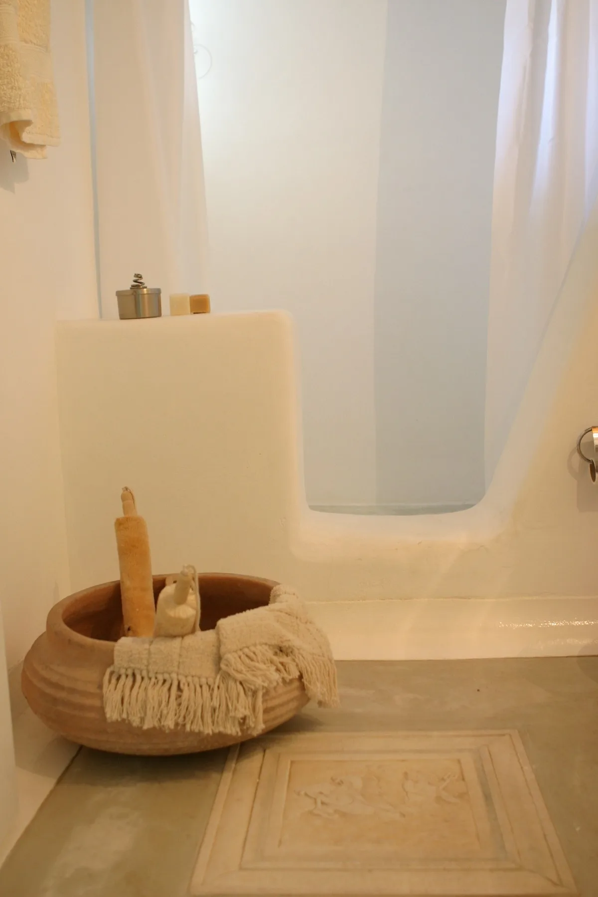 A bathtub with a woven basket of bath items beside it.