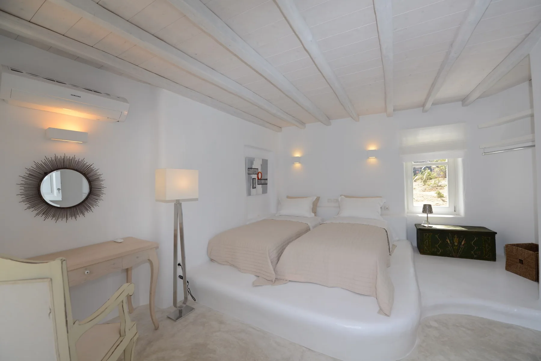 A bright bedroom with a double bed, bedside lamps, and a window.