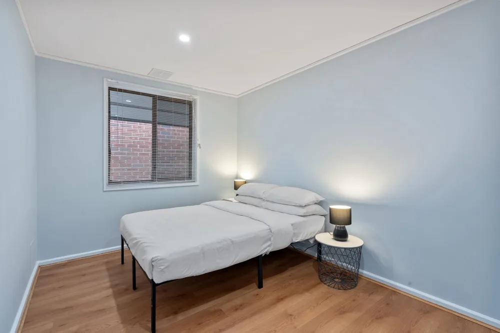 A bedroom with a bed, a window, and a small bedside table.