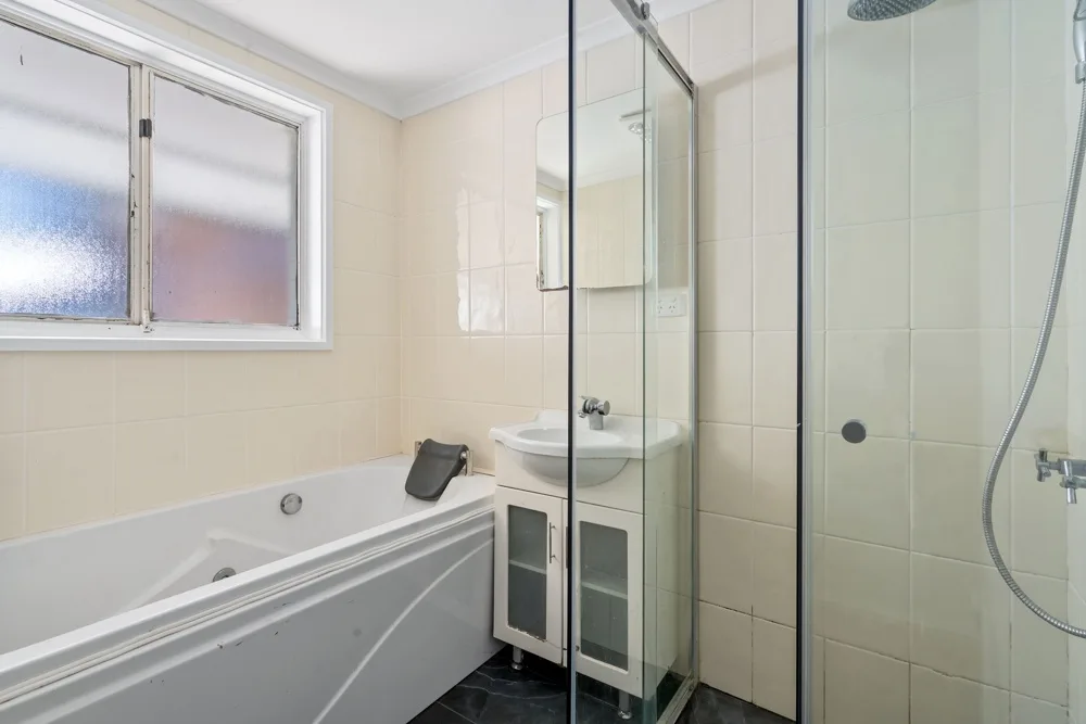 A tiled bathroom with a bathtub, glass shower, and vanity.