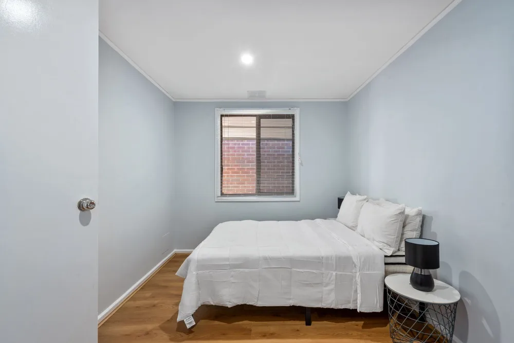 A bedroom with a bed, white bedding, and a window.