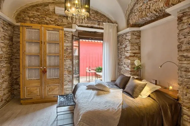 Espacio representativo del hotel: Un dormitorio con una cama junto a una mesita y una puerta abierta.
