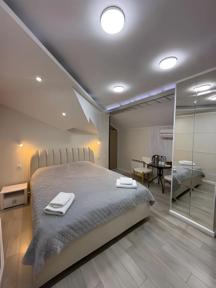 Espacio representativo del hotel: Un dormitorio con la cama tendida y puertas de armario con espejo.