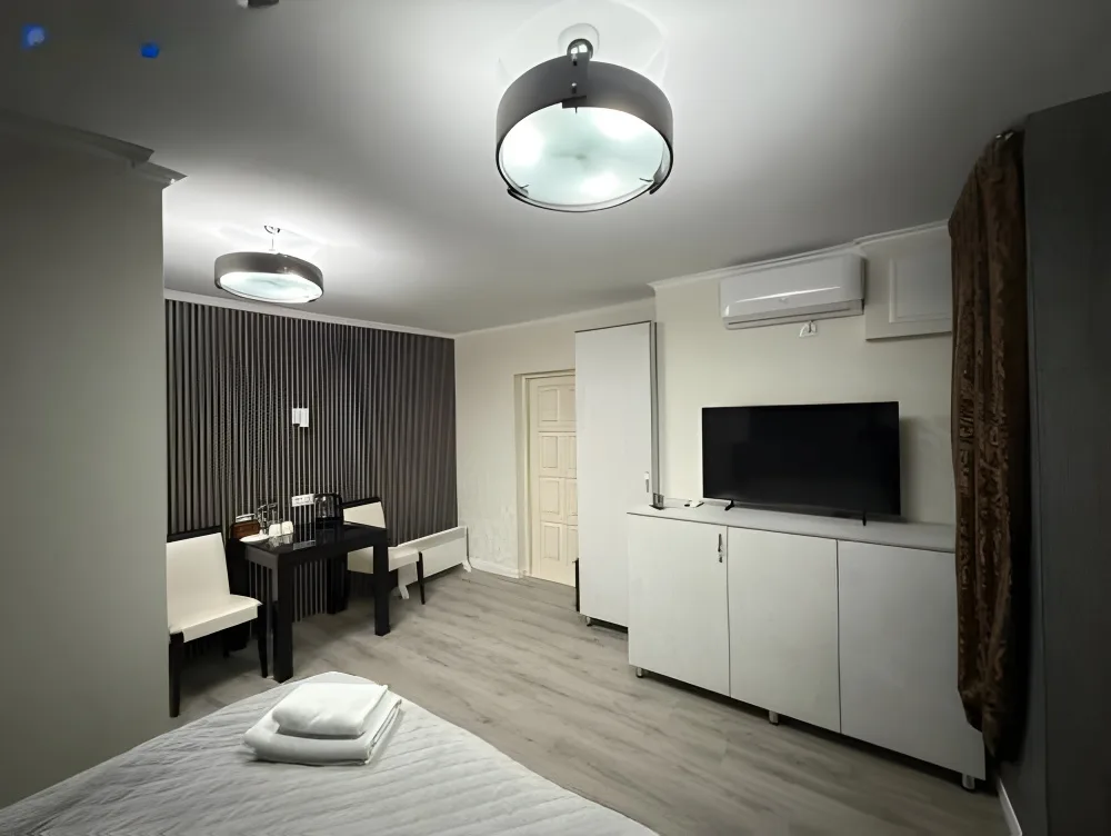 Espacio representativo del hotel: Dormitorio con cama, mesa de comedor y mueble para televisión.