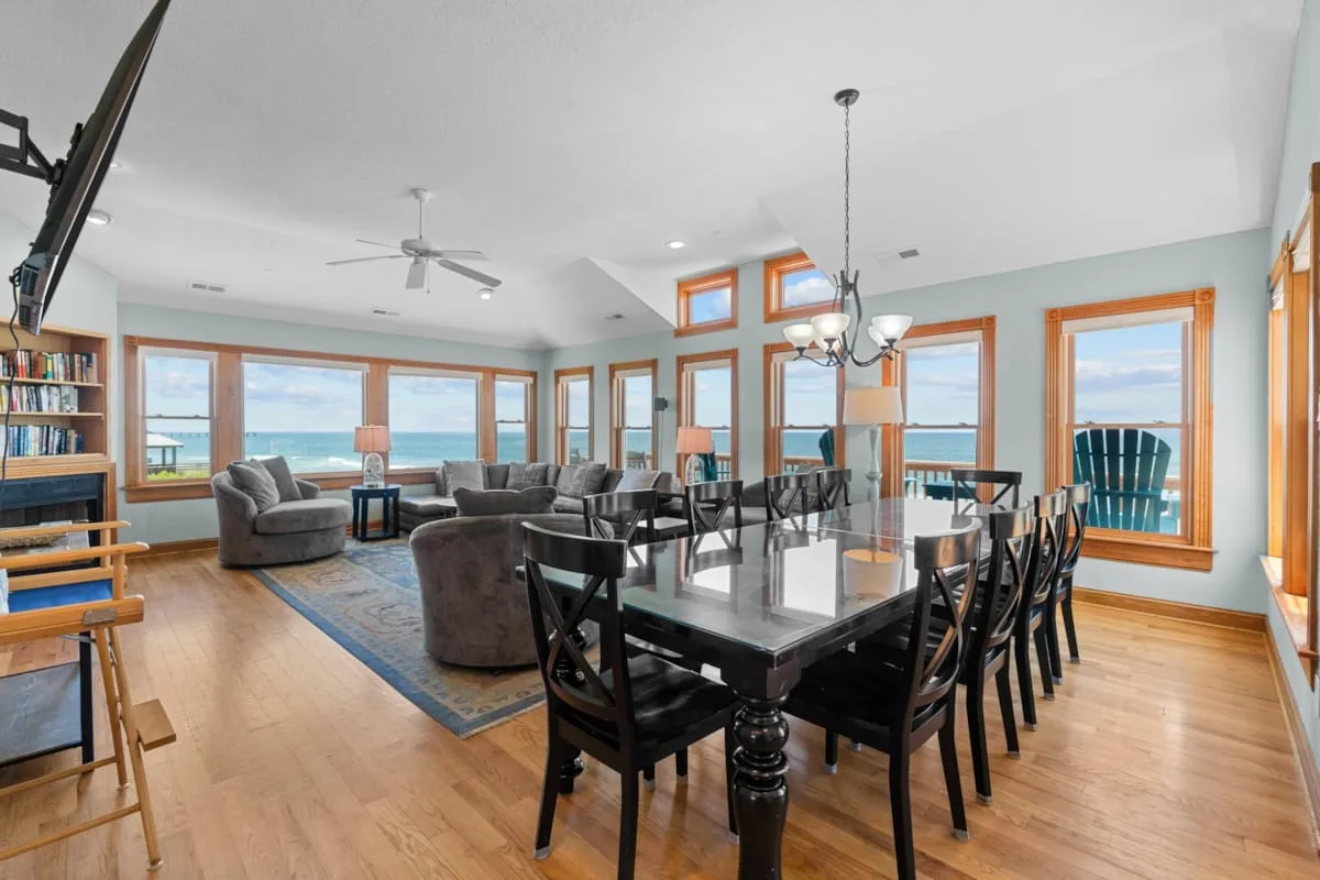 A dining area and living space with large windows overlooking the water.