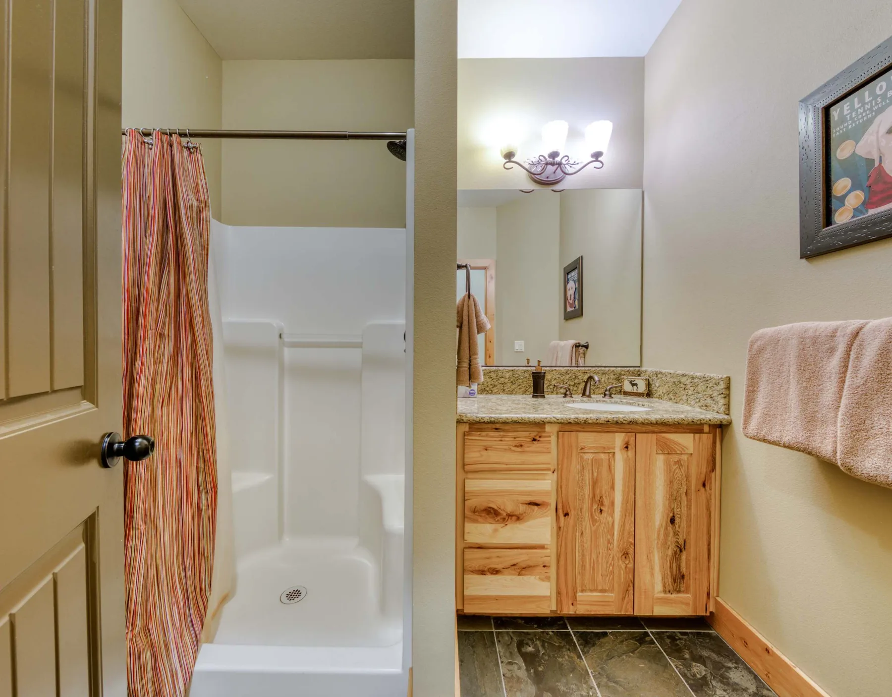 A bathroom with a shower, vanity, and mirror.