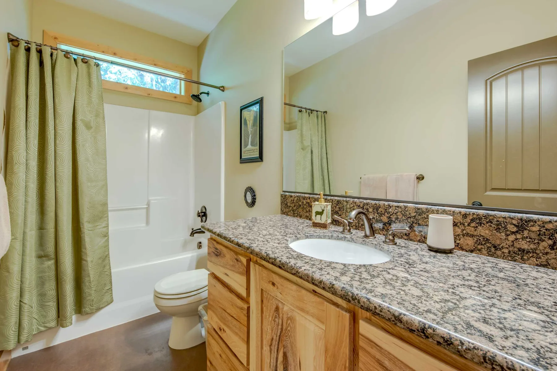 A bathroom with a bathtub, toilet, and long vanity.