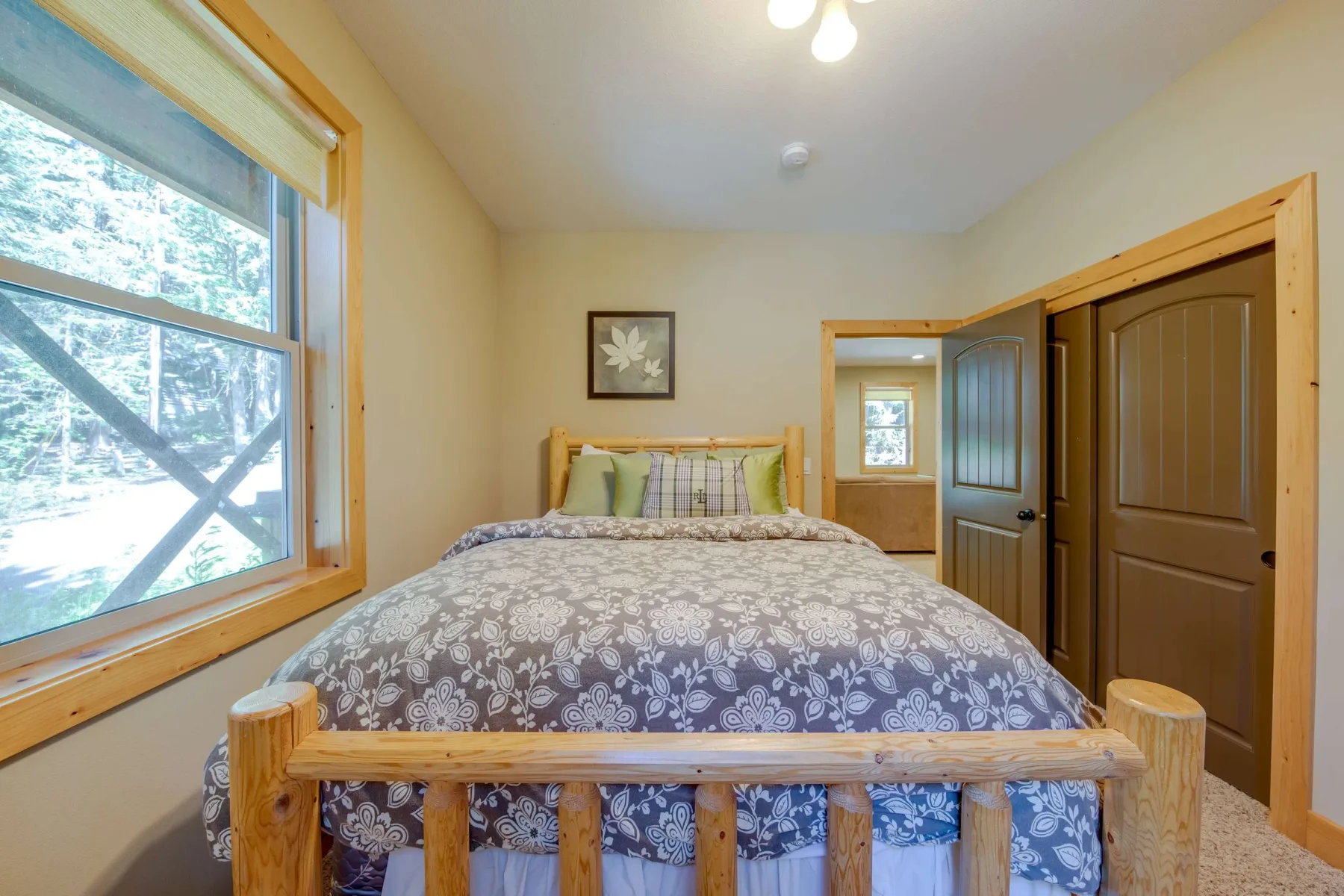 A bedroom with a patterned bedspread and a large window.