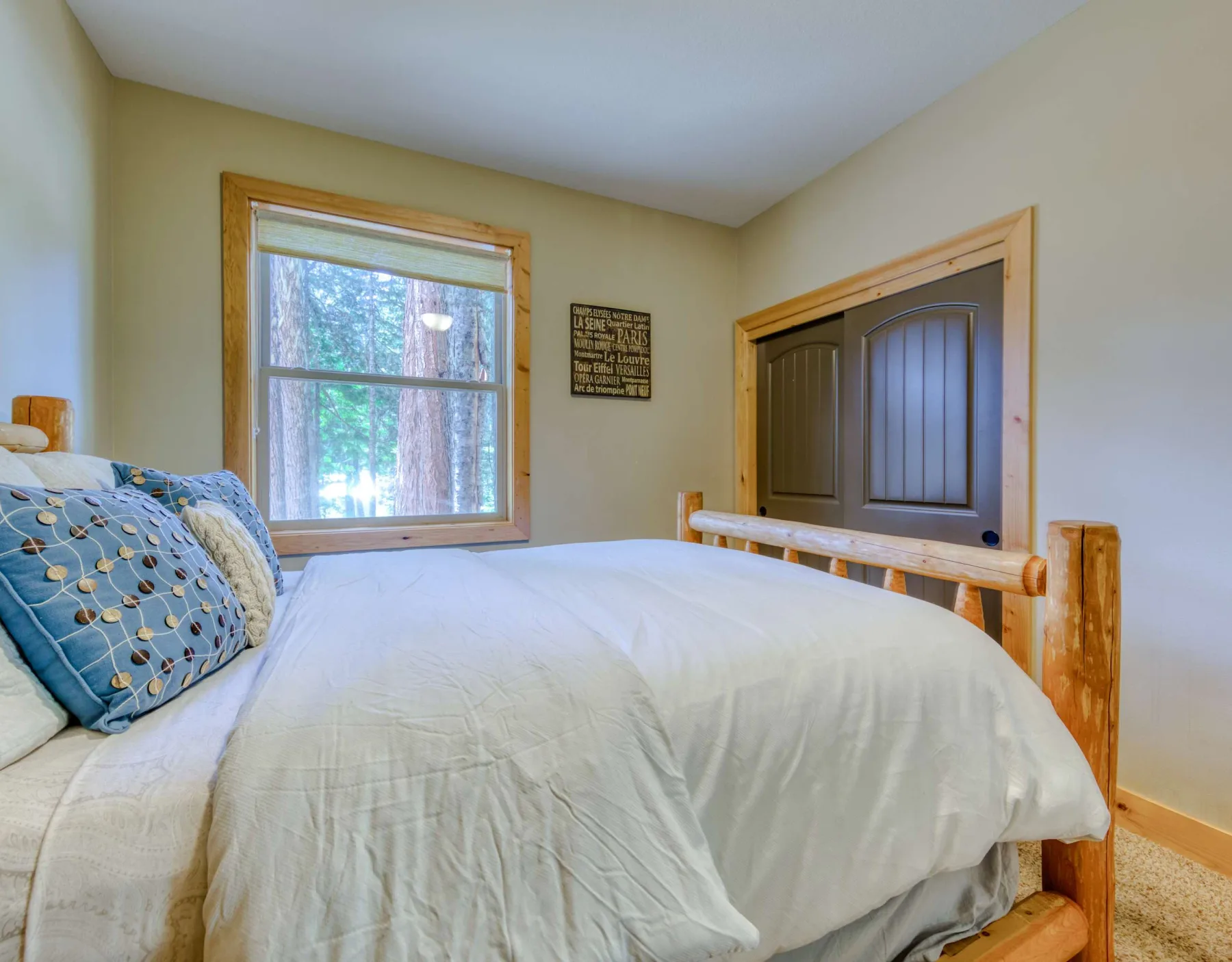A bedroom with a bed beside a window and a wooden bed frame.