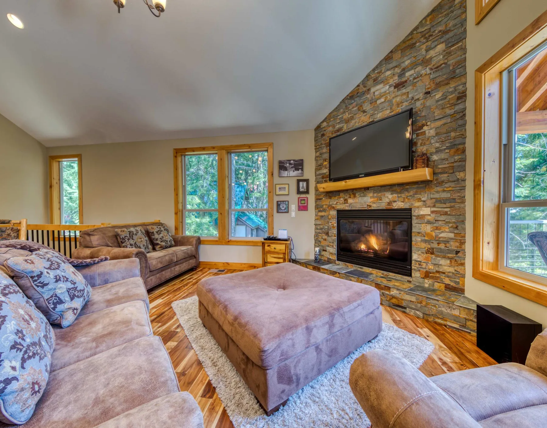 A living room with seating, a fireplace, and a television on a stone wall.