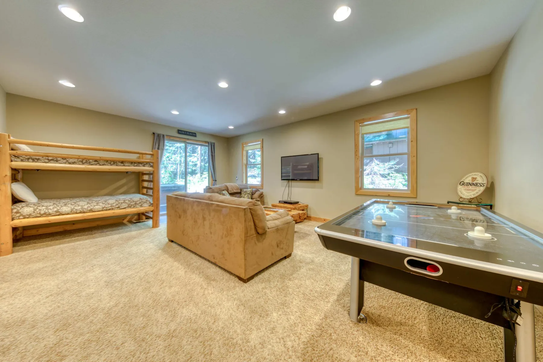A carpeted living and game room with seating, bunk beds, and a pool table.